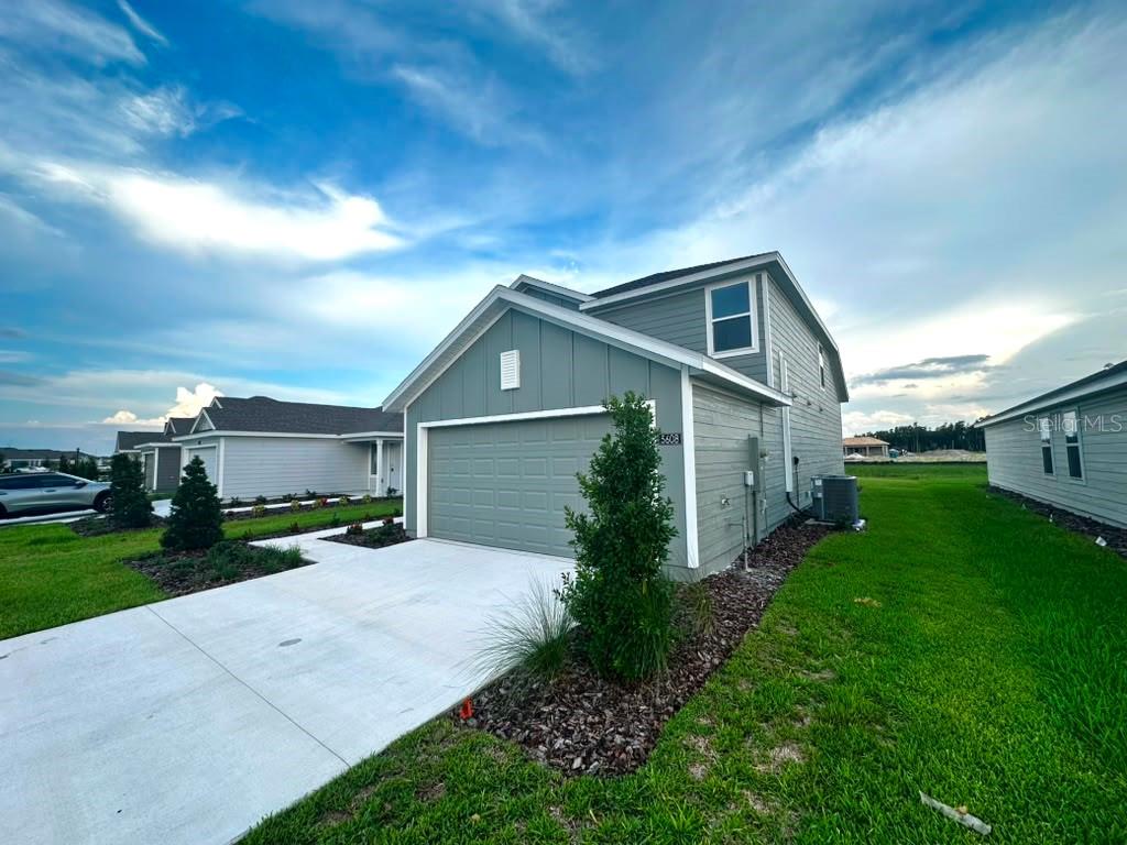 A two-story house with gray siding and a two-car garage under a blue sky — 5608 MORANT BAY PATH, KISSIMMEE, FL
