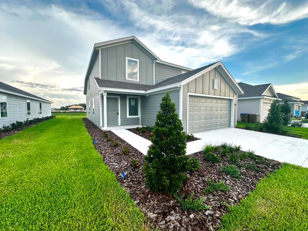 A two-story house with gray vertical siding, a front-facing garage, and a landscaped front yard — 5608 MORANT BAY PATH, KISSIMMEE, FL