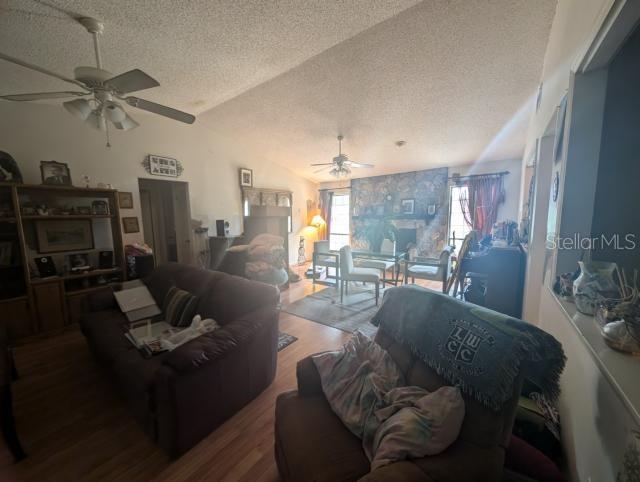 A living room with a stone fireplace, ceiling fans, and wood-style flooring — 4345 OLD COLONY ROAD, MULBERRY, FL