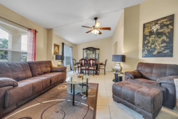 A living room with brown sofas, a glass coffee table, and a dining area beyond — 27 PATRIC DRIVE, PALM COAST, FL