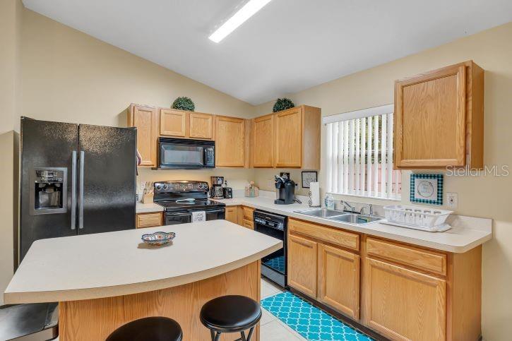 A kitchen features oak cabinets, a black refrigerator, a central island, and a double sink — 27 PATRIC DRIVE, PALM COAST, FL