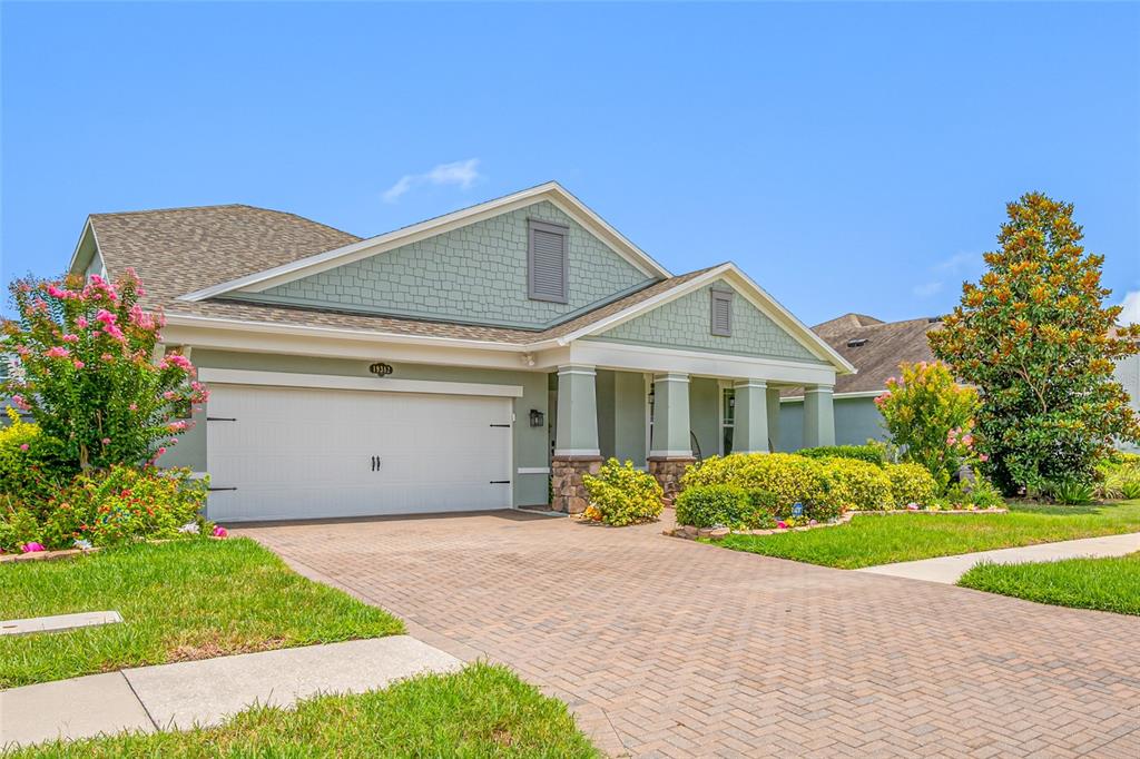 A single-story house with a light green exterior, a two-car garage, and a covered porch — 19382 LONG LAKE RANCH BOULEVARD, LUTZ, FL