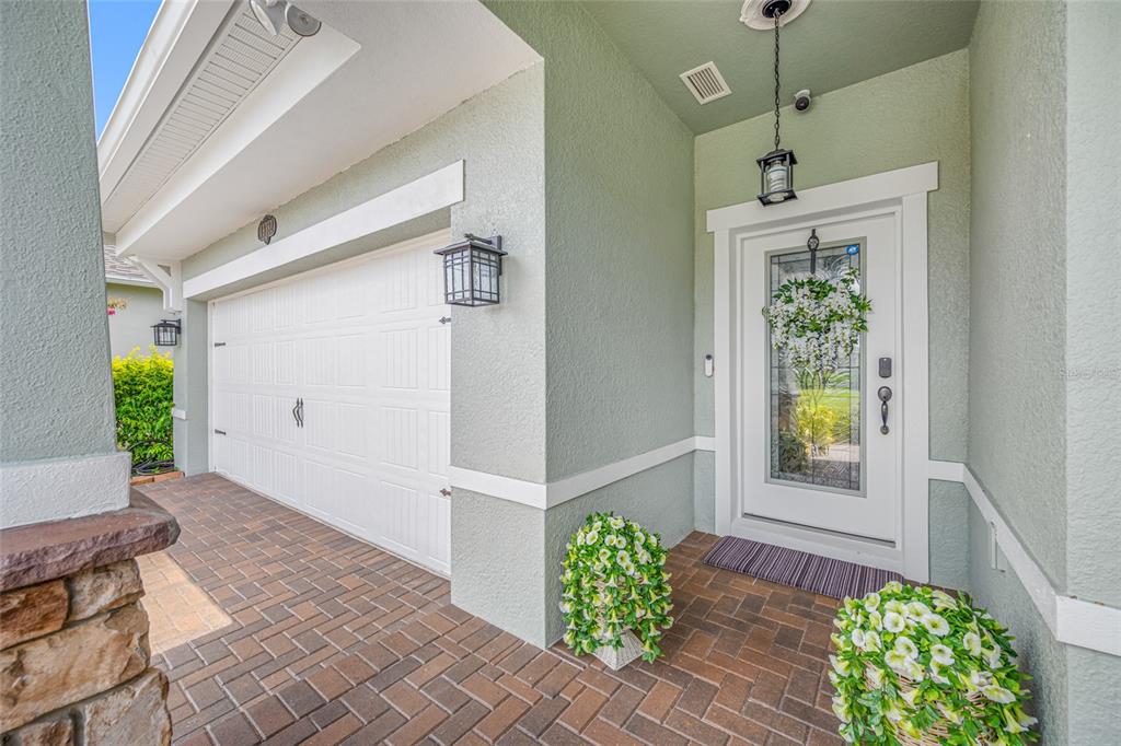 A front entryway with a white garage door, a glass-paneled door, and brick pavers — 19382 LONG LAKE RANCH BOULEVARD, LUTZ, FL