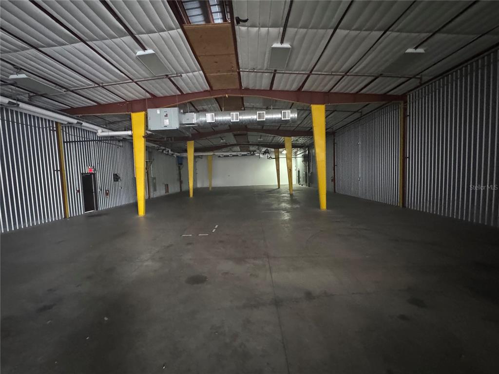An empty industrial warehouse space features metal walls, concrete floors, and yellow support columns — 2251 TOPLINE WAY UNIT 3, BROOKSVILLE, FL