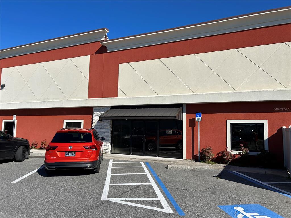 An exterior view of a commercial building with a red facade and a parking lot — 1609 SW 17TH STREET UNIT 400, OCALA, FL