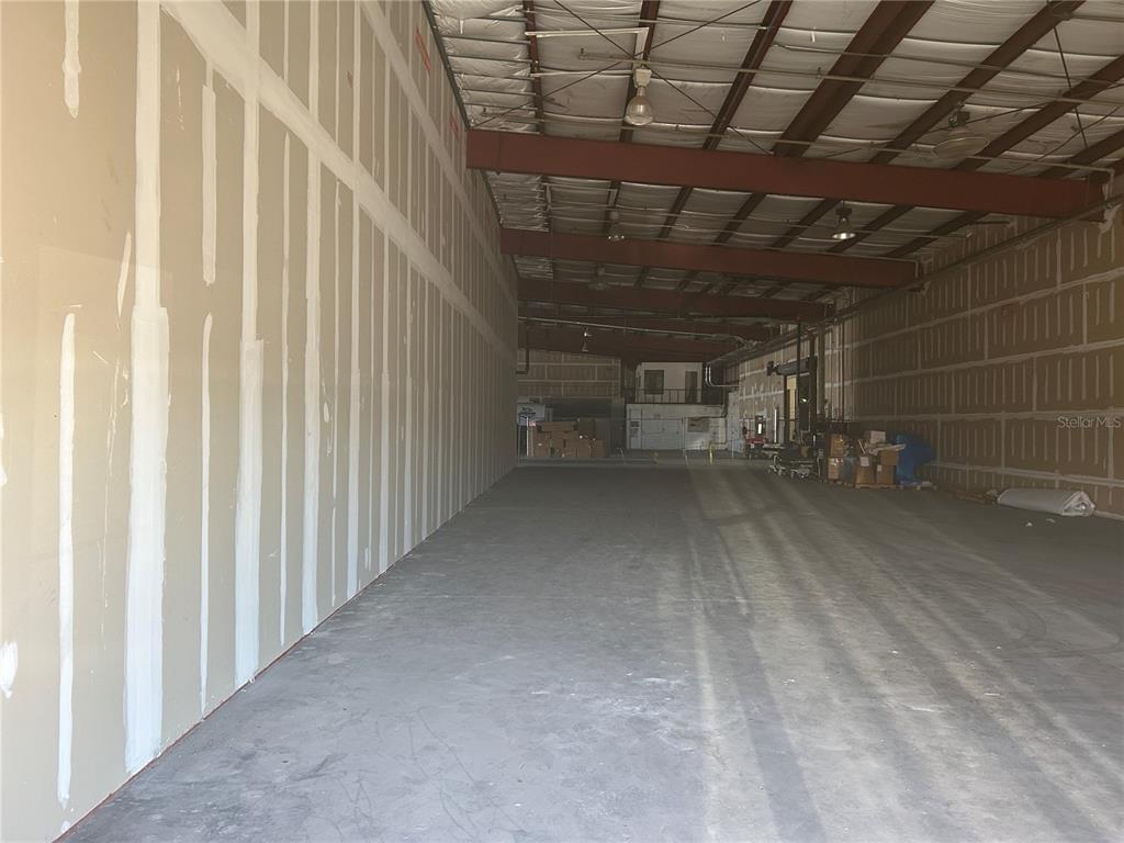 An unfinished warehouse interior features concrete floors, exposed steel beams, and drywall-covered walls — 1609 SW 17TH STREET UNIT 400, OCALA, FL