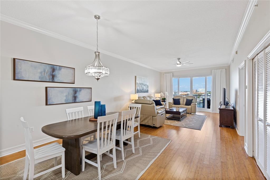 An open-concept living and dining area features hardwood floors, a chandelier, and balcony access — 530 S GULFVIEW BOULEVARD UNIT 601, CLEARWATER BEACH, FL