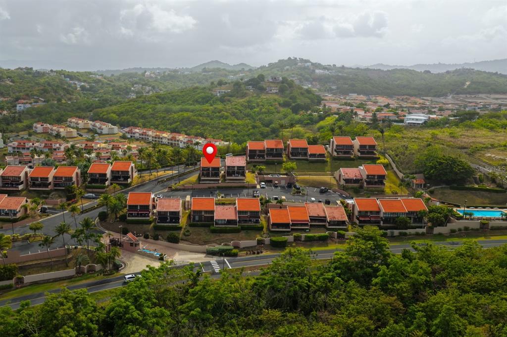 An aerial view shows a residential complex with red-roofed buildings surrounded by lush green hills — 170 PALMAS DR UNIT A1, HUMACAO, PR