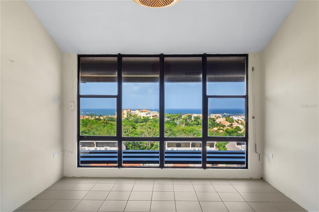 An empty room with light tile flooring and a large window overlooking the ocean — 170 PALMAS DR UNIT A1, HUMACAO, PR