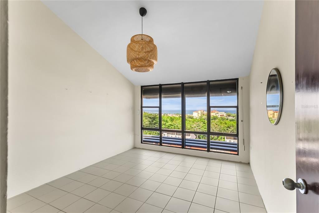 An empty room with light tile flooring, a woven pendant light, and large ocean-view windows — 170 PALMAS DR UNIT A1, HUMACAO, PR