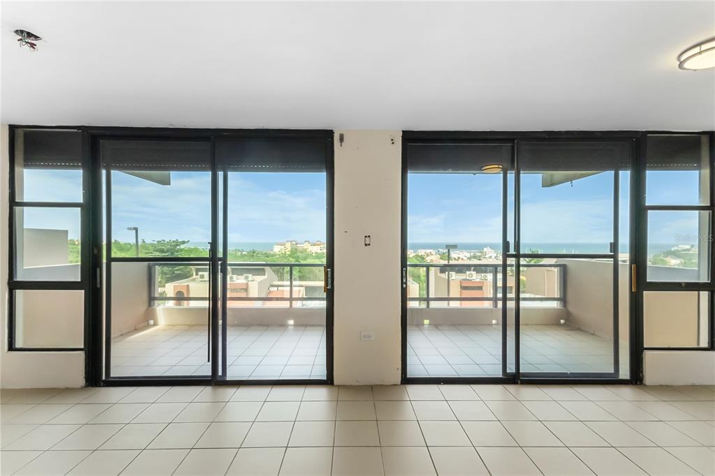 A room with tiled floors and two sets of sliding glass doors leading to a balcony — 170 PALMAS DR UNIT A1, HUMACAO, PR