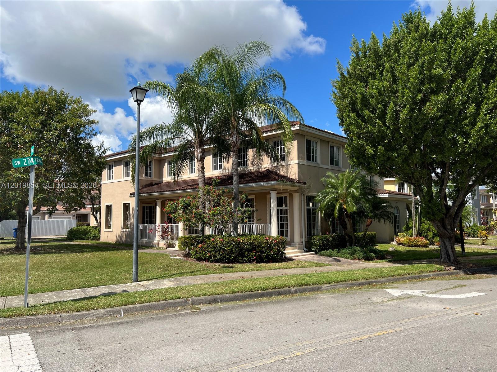 A two-story tan stucco house with a tiled roof and palm trees in the front yard — 14008 SW 274 TER, Homestead FL 33032, HOMESTEAD, FL