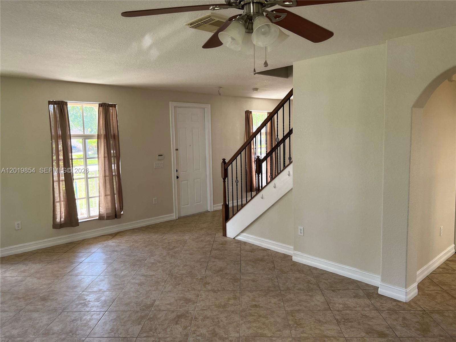 A living room features tile flooring, a staircase with a wooden railing, and a ceiling fan — 14008 SW 274 TER, Homestead FL 33032, HOMESTEAD, FL