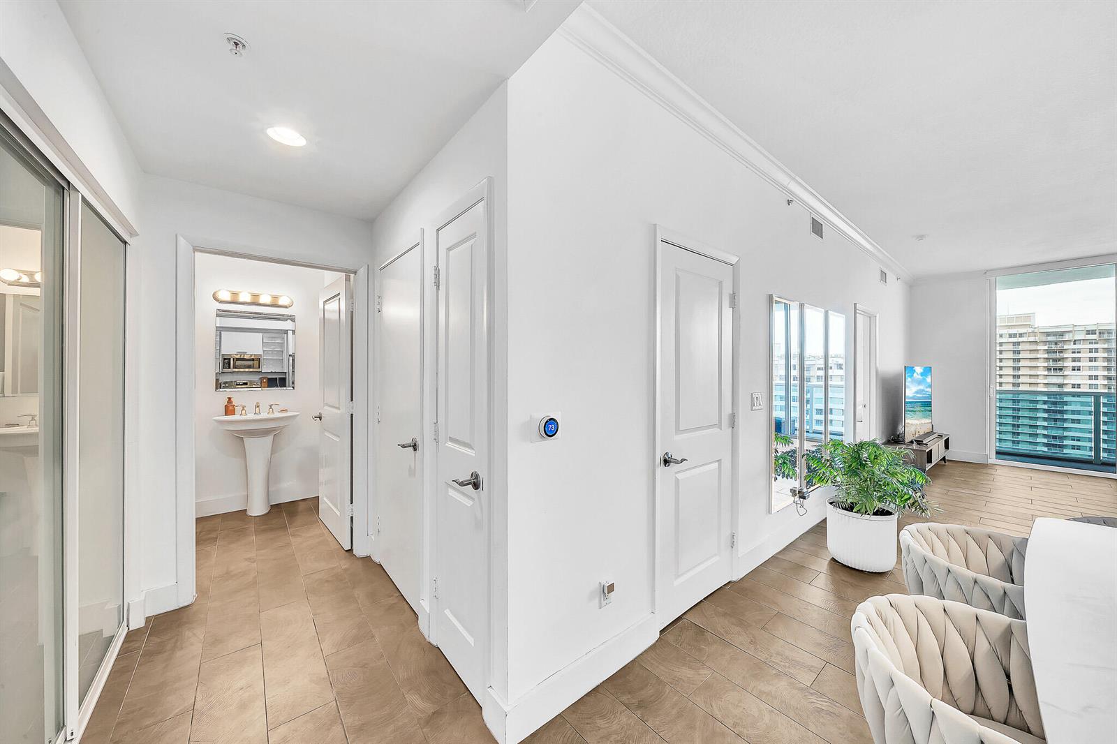 A bright hallway with tiled floors leads to a bathroom and an open living area — 1945 S Ocean Drive # 1803, Hallandale Beach FL 33009, HALLANDALE BEACH, FL