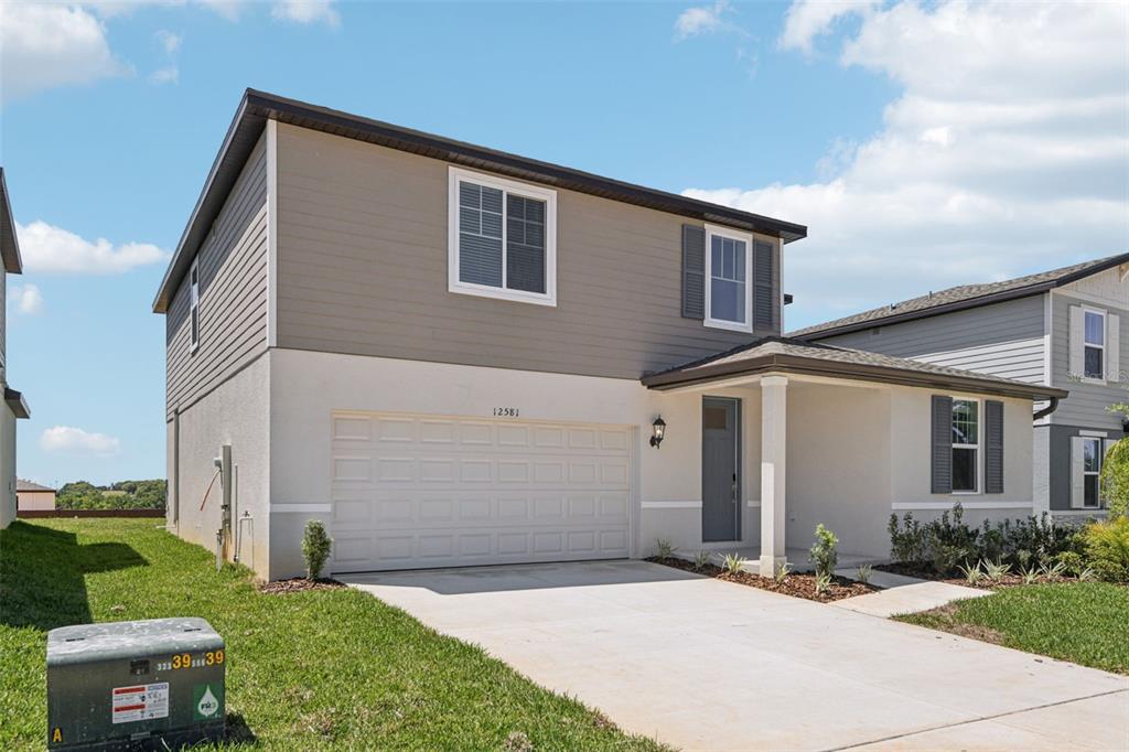 A two-story house with a beige stucco lower level and gray horizontal siding above — 12581 HOMELAND DRIVE, DADE CITY, FL