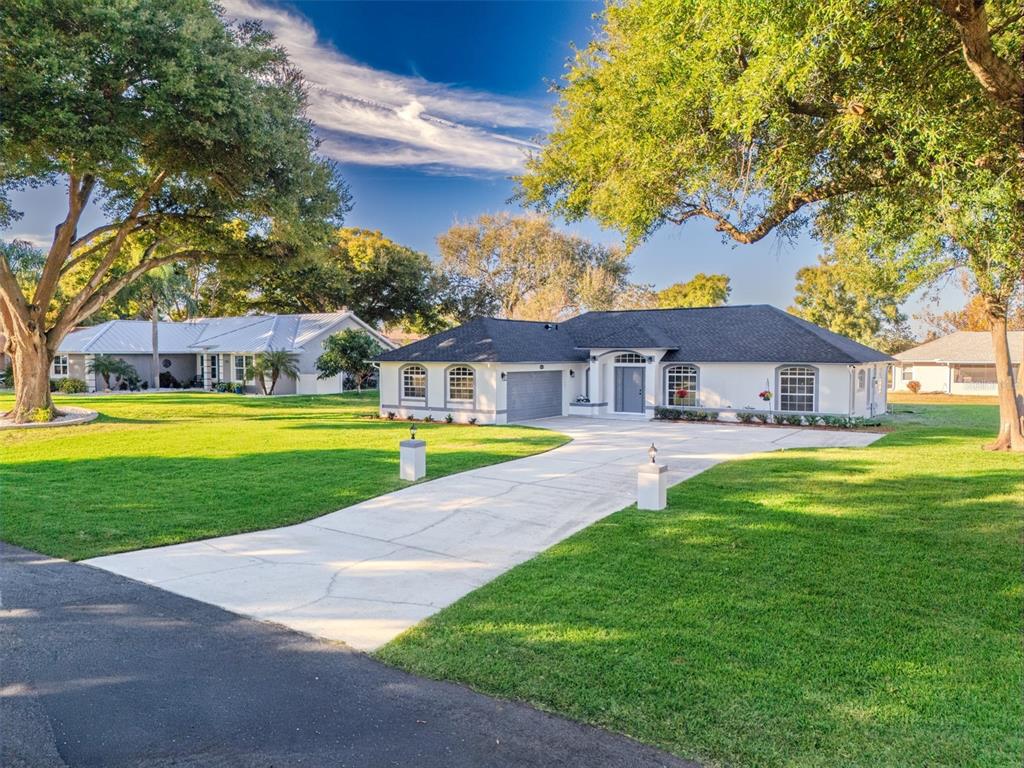 A white single-story house with a dark roof and a concrete driveway sits on grass — 10711 LAKE HILL DRIVE, CLERMONT, FL