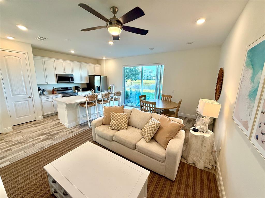 An open-concept kitchen and living area features white cabinetry, a kitchen island, and a sofa — 3165 CARIBBEAN SOUL DRIVE, KISSIMMEE, FL