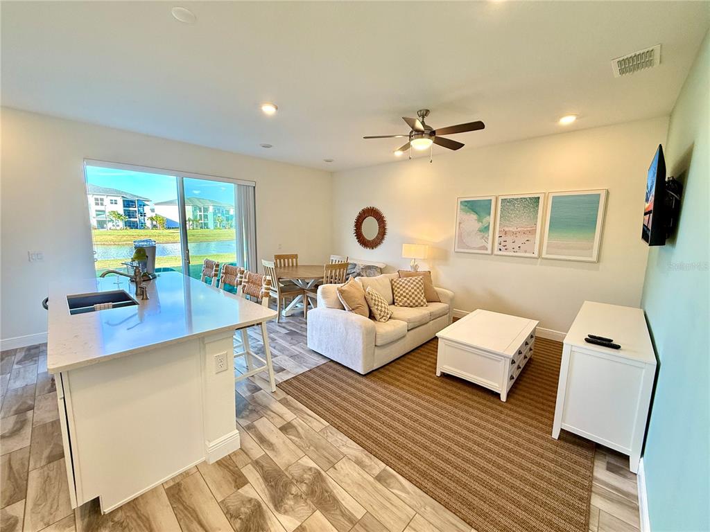 An open-concept living and dining area features a kitchen island, tile flooring, and lake views — 3165 CARIBBEAN SOUL DRIVE, KISSIMMEE, FL