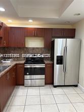 A kitchen with wood cabinets, stainless steel appliances, and light-colored tile flooring — 15139 NE 6th Ave # 3, Miami FL 33162, MIAMI, FL