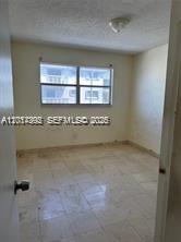 An empty bedroom features light-colored tile flooring, off-white walls, and a window with blinds — 15139 NE 6th Ave # 3, Miami FL 33162, MIAMI, FL