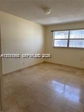 An empty room features light-colored tile flooring, plain walls, and a window with blinds — 15139 NE 6th Ave # 3, Miami FL 33162, MIAMI, FL