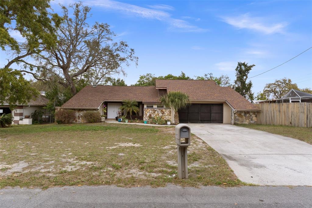 A single-story house with a stone facade, brown shingled roof, and a concrete driveway — 6231 WAYSIDE COURT, SPRING HILL, FL