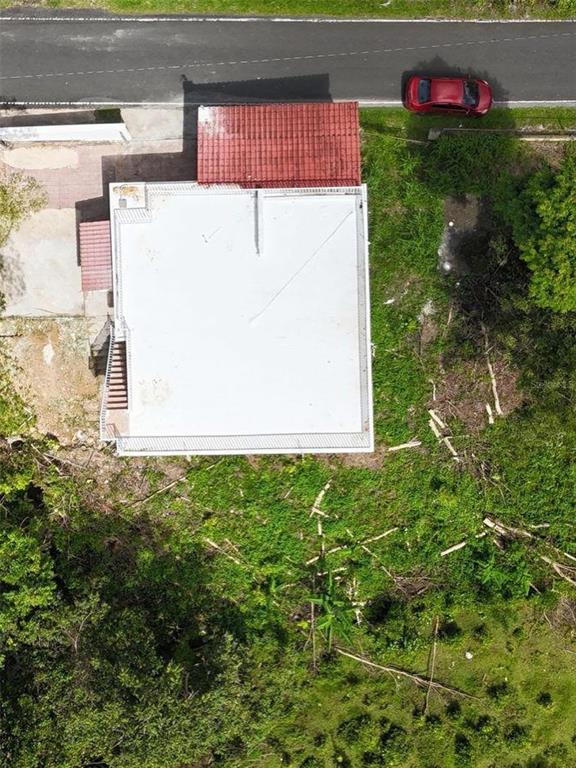 An aerial view shows a house with a flat white roof and a red-tiled entryway — PR 7790 Juan Asencio JUAN ASENCIO, AGUAS BUENAS, PR