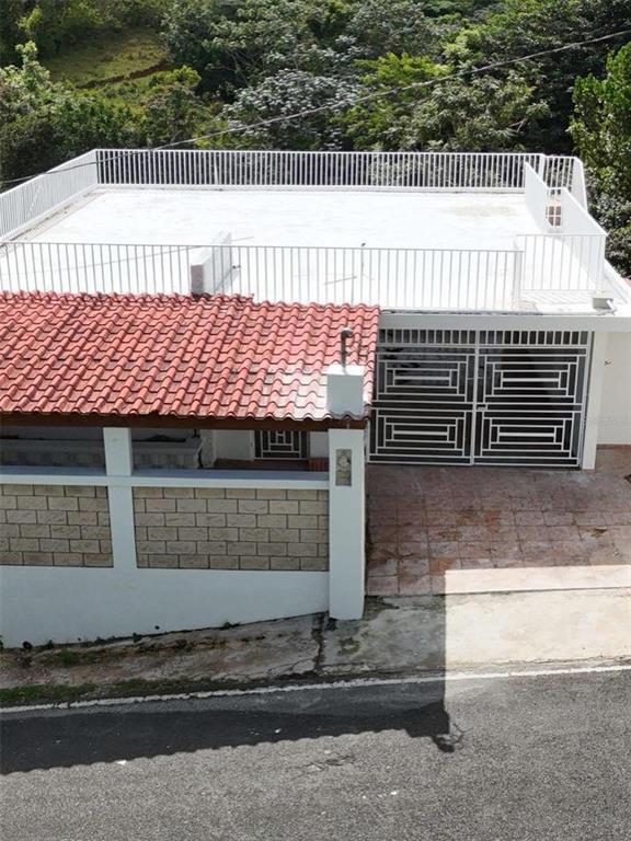 An elevated view of a house with a flat roof terrace and a tiled porch — PR 7790 Juan Asencio JUAN ASENCIO, AGUAS BUENAS, PR