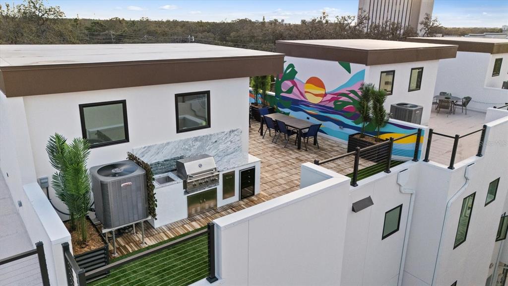 An elevated outdoor rooftop terrace features a built-in kitchen, dining area, and colorful mural wall — 623 PETIT WAY, LARGO, FL