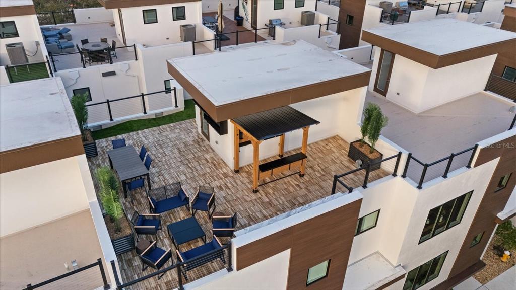 An aerial view of a modern rooftop terrace featuring outdoor furniture, a pergola, and pavers — 623 PETIT WAY, LARGO, FL