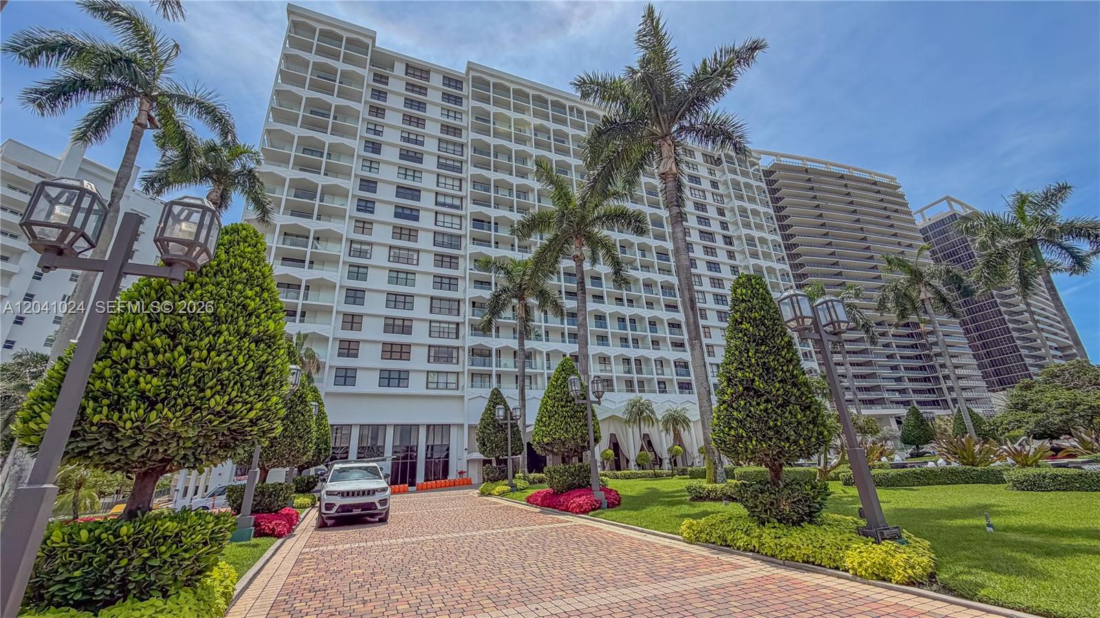 A white high-rise residential building stands behind a paved driveway with palm trees and landscaping — 9801 Collins Ave # 3U, Bal Harbour FL 33154, BAL HARBOUR, FL
