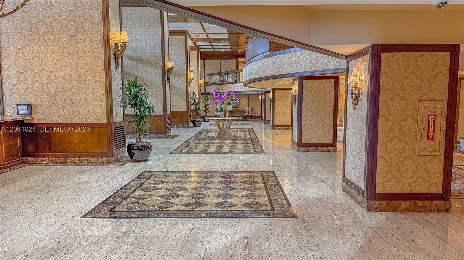 A spacious lobby features marble floors, patterned wallpaper, wall sconces, and decorative tile inlays — 9801 Collins Ave # 3U, Bal Harbour FL 33154, BAL HARBOUR, FL