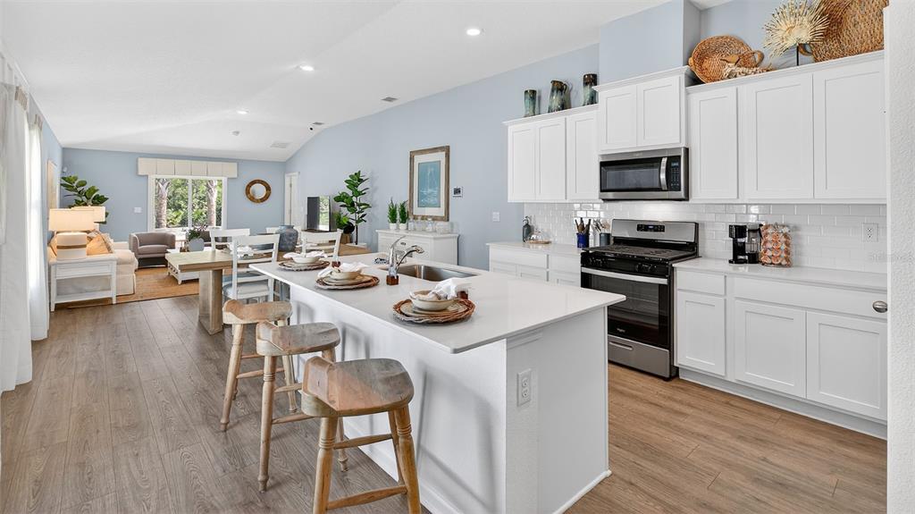 A kitchen with white cabinets and a quartz island overlooks an open-concept living area — 13 DIVOT PLACE, BUNNELL, FL
