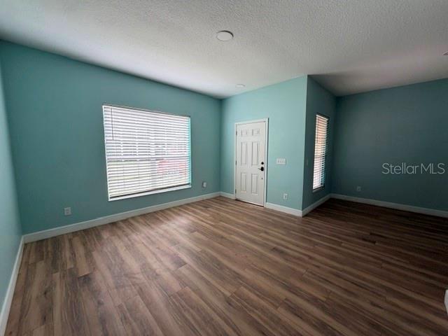 An empty room with light blue walls, wood-look flooring, a window with blinds, and a door — 10640 SUN VILLA BOULEVARD, ORLANDO, FL