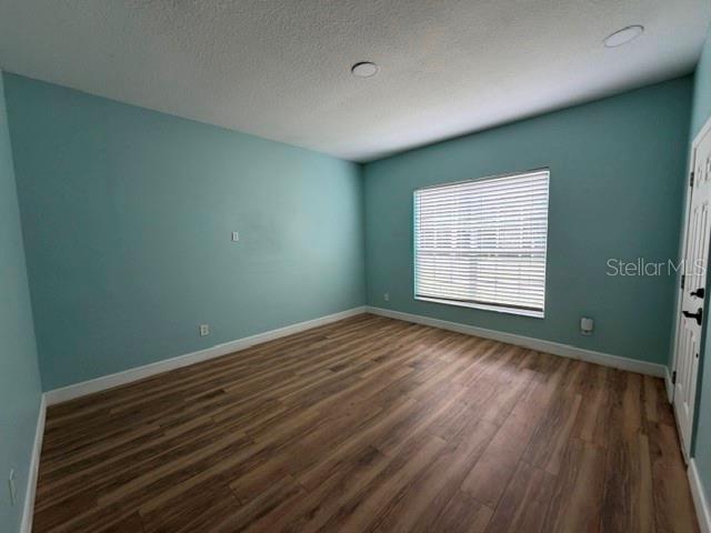 An empty room with light blue walls, wood-look flooring, and a single window with blinds — 10640 SUN VILLA BOULEVARD, ORLANDO, FL