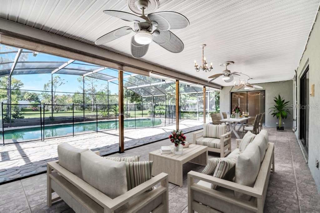 A swimming pool enclosed by a screened lanai with a stone patio and surrounding trees — 3328 WAX BERRY COURT, WINDERMERE, FL