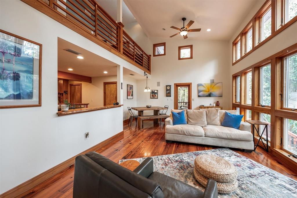 A living room with high ceilings, wooden floors, a loft balcony, and large windows — 22675 NW 75TH AVENUE ROAD, MICANOPY, FL