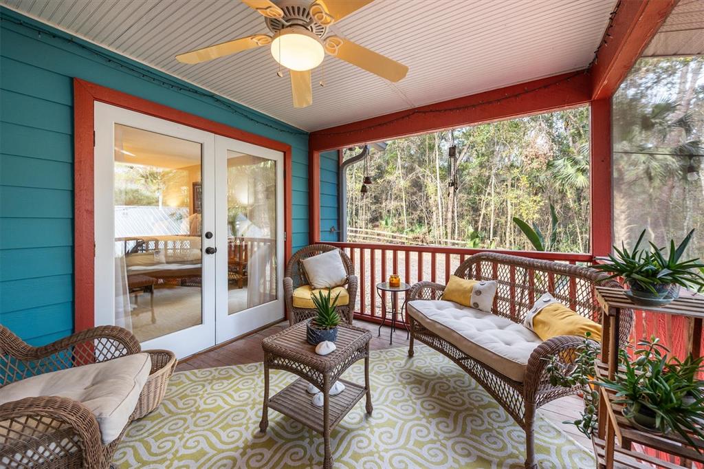 A screened-in porch features wicker furniture, a patterned rug, and a ceiling fan — 22675 NW 75TH AVENUE ROAD, MICANOPY, FL