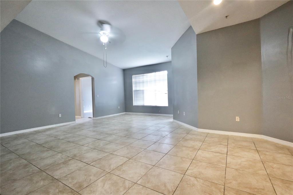 An empty room features gray walls, light-colored tile flooring, and a ceiling fan — 5578 METROWEST BOULEVARD UNIT 1-201, ORLANDO, FL