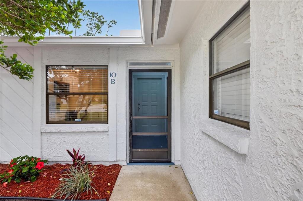 The exterior entrance of a white stucco building features a screen door and unit number — 10 BREN MAR LANE, PALM COAST, FL
