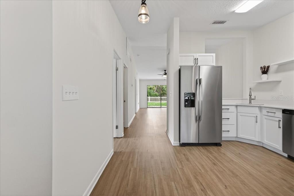 A kitchen with stainless steel appliances and white cabinets opens to a hallway and backyard — 10 BREN MAR LANE, PALM COAST, FL