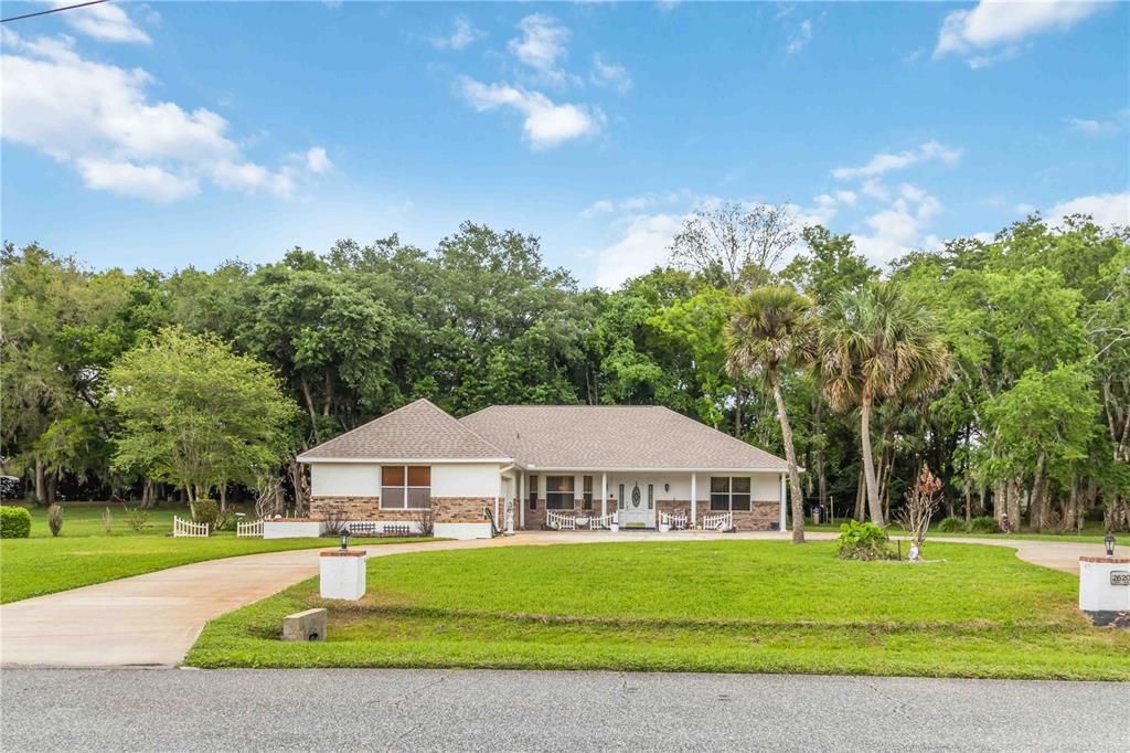 A single-story house with a brick and stucco exterior sits behind a grassy front lawn — 2620 TOUPS TRAIL, TITUSVILLE, FL