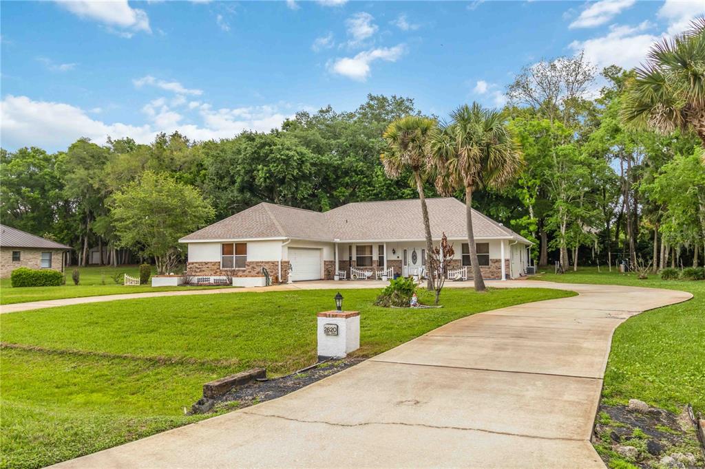 A single-story house with a white exterior, stone accents, and a curved concrete driveway — 2620 TOUPS TRAIL, TITUSVILLE, FL