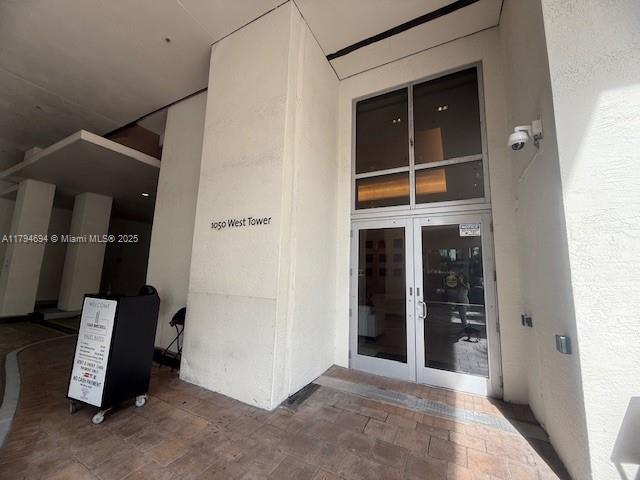 The exterior entrance of a building features a glass door, a security camera, and a sign — 1050 Brickell Ave # 1602, Miami FL 33131, MIAMI, FL