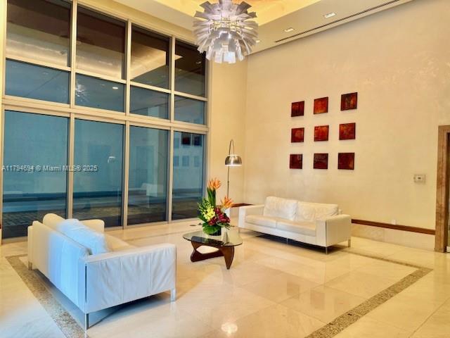 A bright, high-ceilinged lobby features two white sofas, a glass coffee table, and wall art — 1050 Brickell Ave # 1602, Miami FL 33131, MIAMI, FL