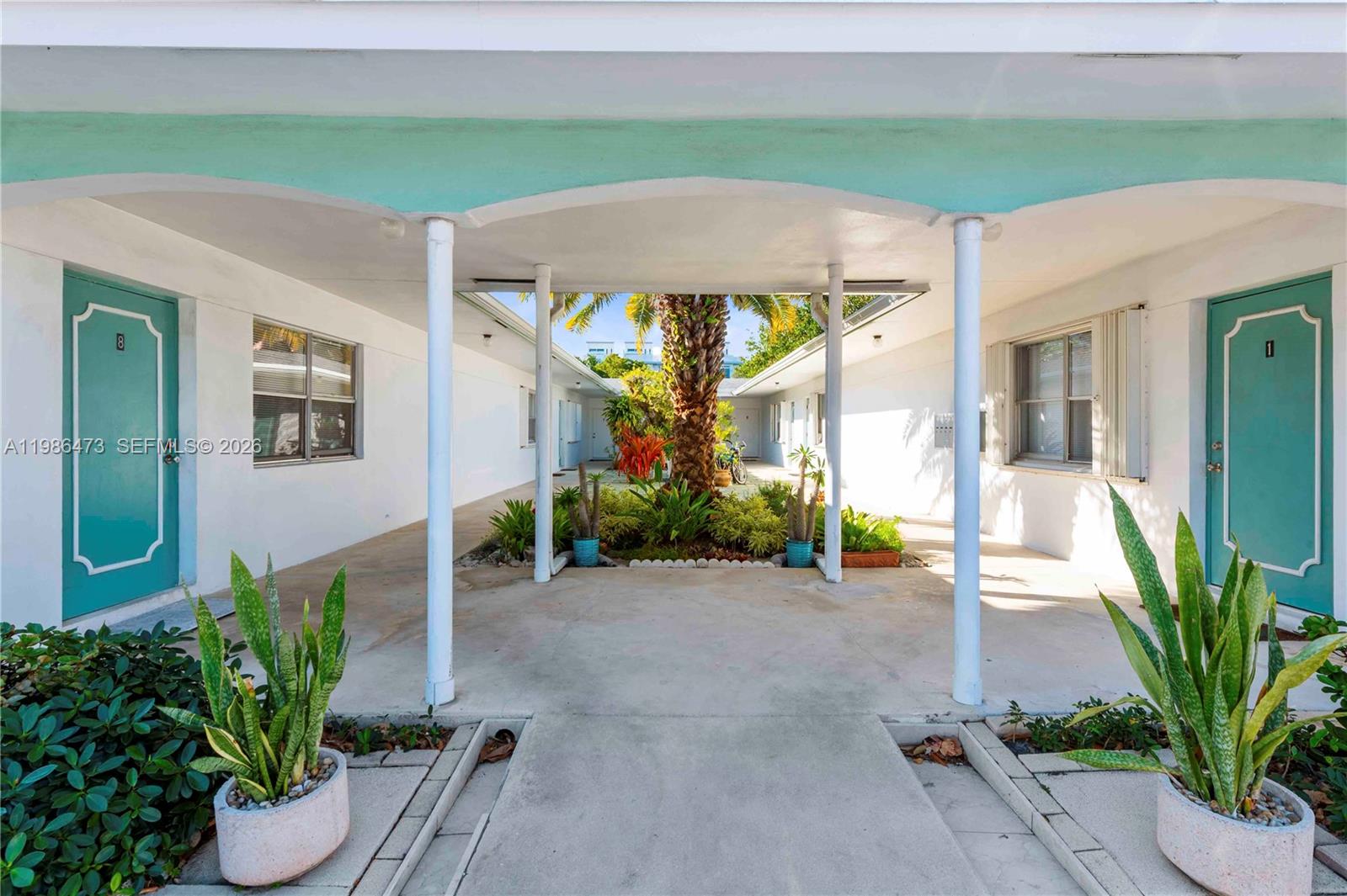 An outdoor courtyard with a central palm tree sits between two rows of apartment units — 3240 NE 16th St # 3, Pompano Beach FL 33062, POMPANO BEACH, FL