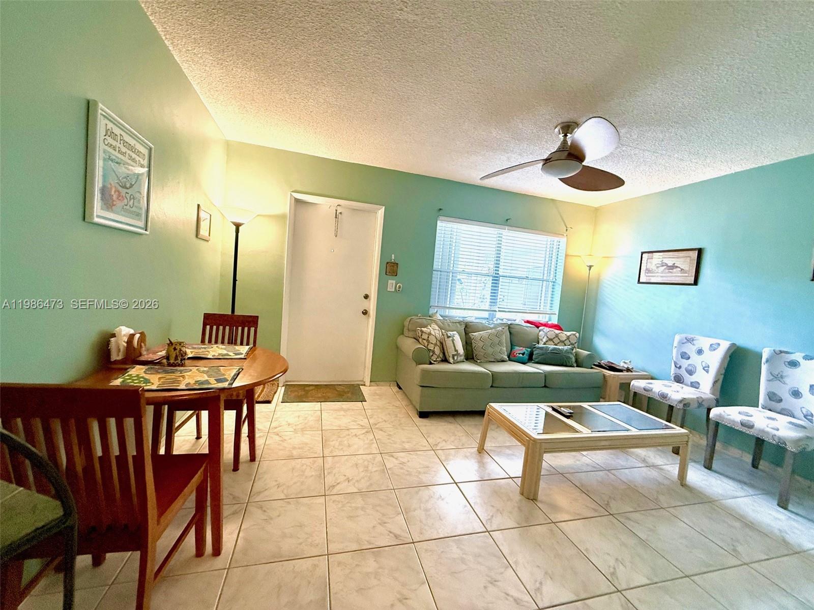 A living and dining area features light green walls, tile flooring, and a ceiling fan — 3240 NE 16th St # 3, Pompano Beach FL 33062, POMPANO BEACH, FL