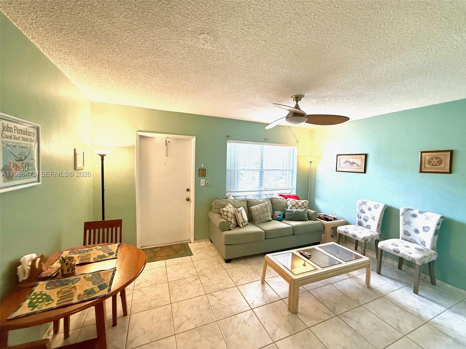 A living room with light green walls, tile flooring, a sofa, and a dining table — 3240 NE 16th St # 3, Pompano Beach FL 33062, POMPANO BEACH, FL