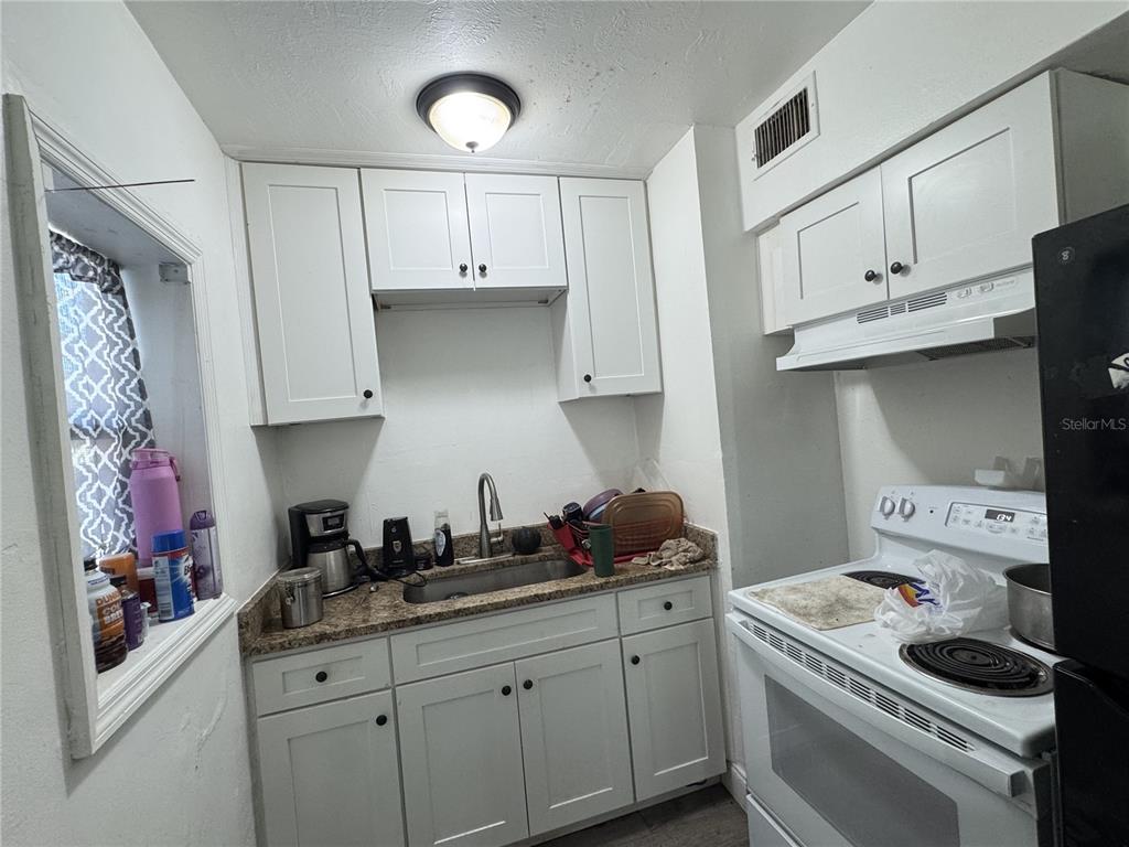 A kitchen features white cabinets, a stainless steel sink, and a white electric range — 5001 CORTEZ DRIVE, ORLANDO, FL