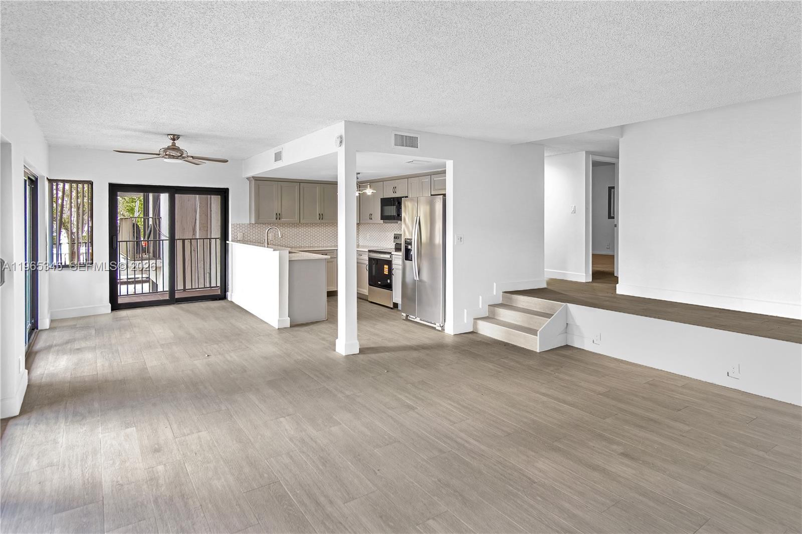 An open-concept living area features light wood-look flooring, a kitchen, and a raised platform — 4705 SW 62nd Ave # 204, Davie FL 33314, DAVIE, FL